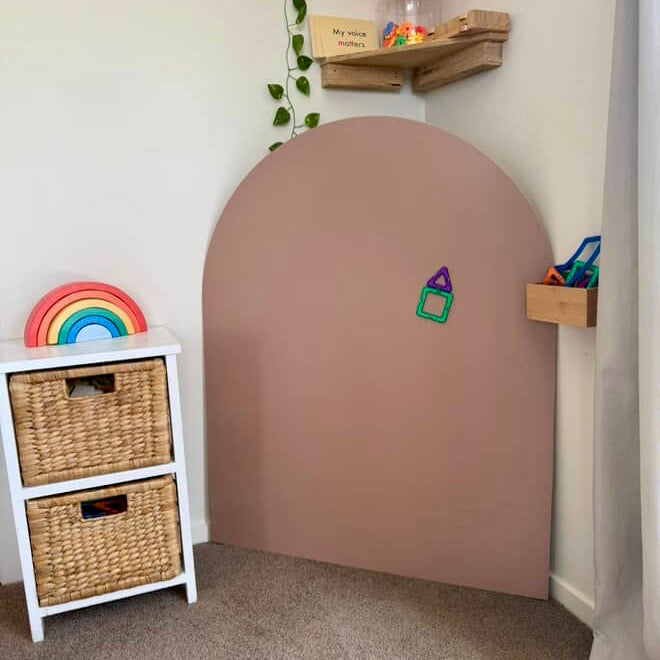 Children's play corner with the ROsewood Magnetic Playwall arch on MDF, white shelf with baskets, and colorful toys including magnetic tiles.