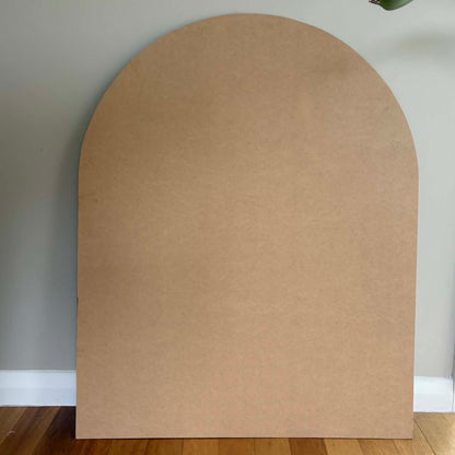 Arch-shaped MDF board piece against a neutral wall. MDF baxkboard for the MAgnetic Playwall by Peasy Play. 